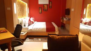 巴特那THE RED VELVET HOTEL的红色的房间,配有一张床和一张桌子及椅子