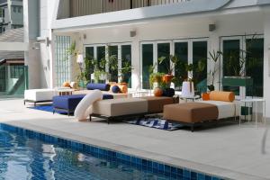 曼谷Le Tada Residence - SHA Plus的游泳池旁的游泳池配有长沙发和椅子