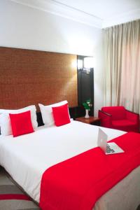 突尼斯hôtel LE PACHA的酒店客房设有一张大床和一张红色椅子。