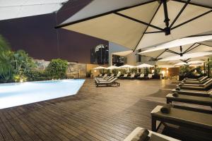 罗安达热带酒店的一个带游泳池、遮阳伞和椅子的酒店