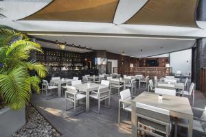 罗安达热带酒店的一间设有白色桌椅的餐厅和一间酒吧