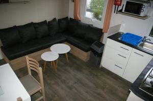 翁赞mobil home 32 m² 4/6p的客厅配有黑色沙发和2张桌子