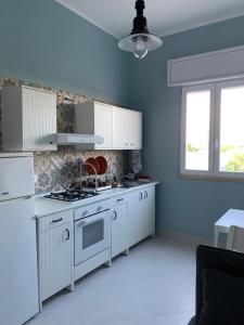 普尔萨诺appartamento VENTO的厨房配有白色橱柜和炉灶烤箱。