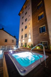 奥斯塔HB Aosta Hotel & Balcony SPA的夜间在大楼前的热水浴池