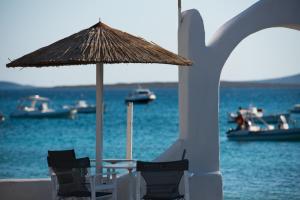艾丽奇Ostria Studios & Apartments的海滩上配有桌椅和遮阳伞