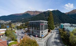 皇后镇Ramada Queenstown Central的一座位于城市街道上的建筑,以群山为背景