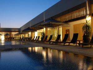 麦纳麦InterContinental Bahrain, an IHG Hotel的一座带椅子和遮阳伞的游泳池位于一座建筑旁边