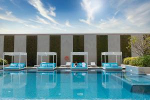 麦纳麦InterContinental Bahrain, an IHG Hotel的一个带蓝色椅子的游泳池,一个坐在里面的人