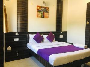 孟买Hotel Amber-colaba的一间卧室配有一张带紫色枕头的大床
