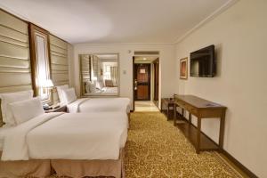 卡拉奇卡拉奇明珠大陆酒店的酒店客房设有两张床、一张桌子和一台电视。