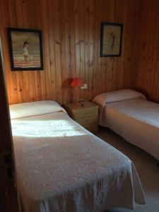 卡尔瓦略Bungalow 3 (adosado) - Playa Arnela的一间卧室配有两张床和床头灯。