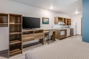 法明顿希尔斯WoodSpring Suites Detroit Farmington Hills的客房设有一张桌子、一台电视和一张床