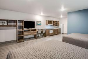 法明顿希尔斯WoodSpring Suites Detroit Farmington Hills的酒店客房设有两张床和一张书桌及电视