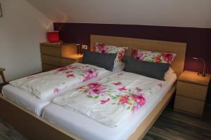 巴特塞森多夫Ferienwohnungen Lohner Höhe的一张床上有白色床单和粉红色的鲜花