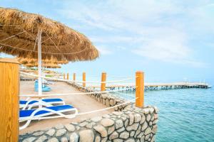 沙姆沙伊赫Sunrise Diamond Beach Resort -Grand Select的海滩上设有椅子和草伞,水面