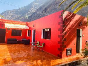 弗龙特拉Pensión Casa Trudo的一座红色的房子,配有桌椅,山