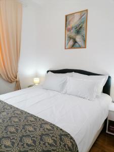 斯雷姆斯卡米特罗维察Apartman Mia的卧室配有一张白色床,墙上挂着一幅画
