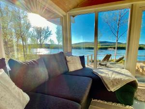 NuorgamAurora mökki porealtaalla Lapissa Tenojoen rannassa的带沙发和大窗户的客厅