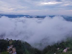 西姆拉Conifers Deluxe Room的雾和云覆盖的山脉景色