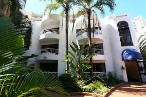 黄金海岸圣特罗佩度假酒店的一座白色的建筑,前面有棕榈树