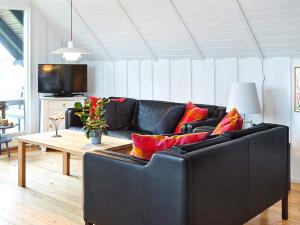 EbbeløkkeHoliday home Nykøbing Sj XXIX的客厅配有黑色沙发和桌子