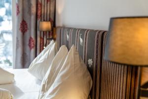 拉姆绍达赫斯坦Aktivhotel Pehab的一间卧室配有带白色枕头和灯的床