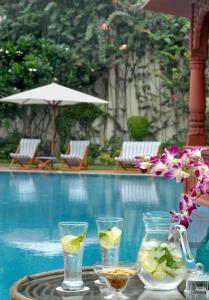 阿格拉格兰德皇家遗址酒店的游泳池畔的桌子上摆放着饮料和鲜花
