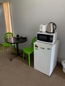 HopetounHOPETOUN COMMUNITY HOTEL MOTEL的小桌子和冰箱上方的微波炉