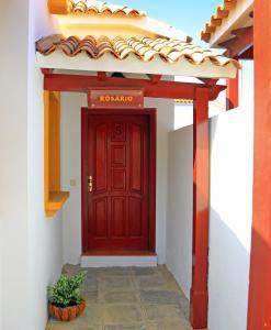 卡勒达德福斯特卡勒塔多拉达VIP别墅酒店的白色建筑中一扇红门,有盆栽