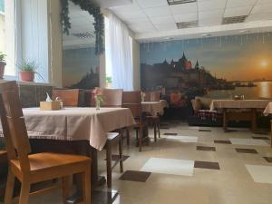 尼古拉耶夫卡拉维拉酒店的餐厅设有桌椅,墙上挂有绘画作品
