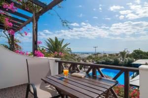 佩里沃罗Holiday Beach Resort Santorini的阳台上的木桌,备有一杯橙汁