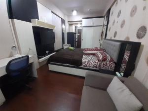 玛琅Apartemen SUKARNO HATTA Elwarda Ely的一间卧室配有一张床、一张沙发和一台电视
