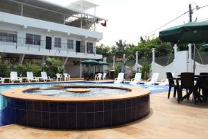 梅尔加Hotel Cacique Guaicani的一个带游泳池和桌椅的度假酒店