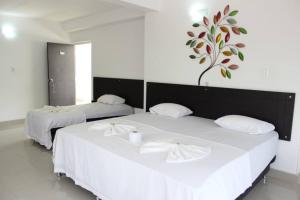 梅尔加Hotel Cacique Guaicani的墙上有一棵树的房间,配有两张白色的床