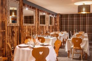 拉茹杜罗普l'Ecrin des Neiges的餐厅配有白色的桌椅和镜子