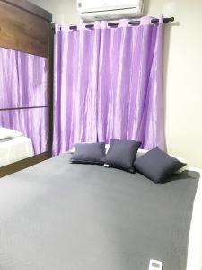 马卡帕Quarto - Condomínio的一间卧室配有紫色窗帘和一张带枕头的床