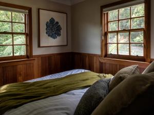MeanderCedar Cottage Meander的一间卧室设有2个窗户和1张床