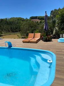 IbicaréSítio com Piscina e Vista a 12km de Treze Tílias的一个带两把椅子和遮阳伞的游泳池