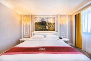 天津天津金泽大酒店的卧室配有一张白色大床,墙上挂有绘画作品