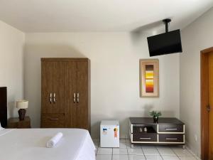 阿纳波利斯B & A Suites Inn Hotel - Quarto Luxo Premium的卧室配有一张床,墙上配有电视。