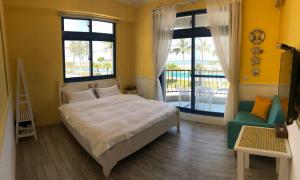 花莲市白色沙滩民宿的一间卧室配有一张床、一把椅子和窗户。