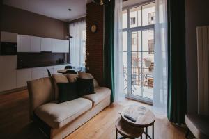 罗兹Apartament Green - Piotrkowska 37的带沙发和大窗户的客厅