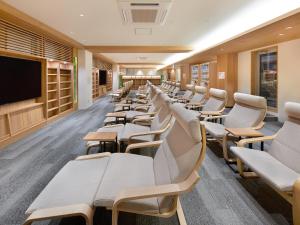 东京Smart Stay SHIZUKU Shinagawa-Oimachi的一间设有白色椅子和平面电视的等候室