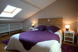 Dompierre-les-ÉglisesLe Moulin du Château的一间卧室配有一张大床,提供紫色床单和枕头
