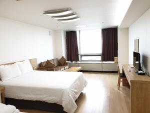 仁川市爱特尔好日子旅馆的酒店客房配有床、沙发和电视。