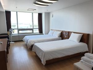 仁川市爱特尔好日子旅馆的酒店客房设有两张床和大窗户。