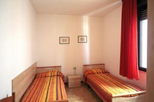 卡奥莱Panfilo的卧室内的两张床,配有红色窗帘