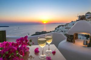 伊亚卡斯特罗伊亚别墅酒店的两杯葡萄酒坐在桌子上,边欣赏日落