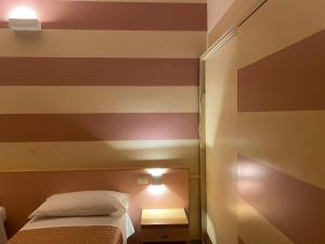 切塞纳萨维奥酒店的一间设有一张床和条纹墙的房间