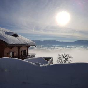 Foncine-le-HautLes Genévriers的雪覆盖的房屋,有太阳背景